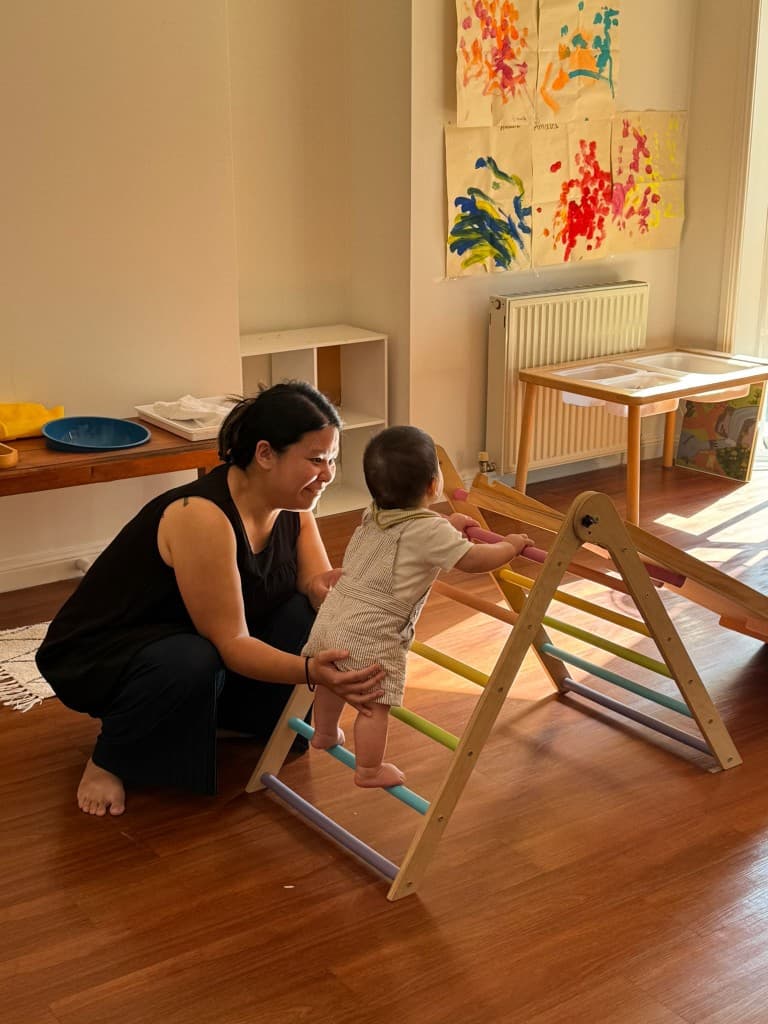 Baby climbing Pikler triangle with parent support